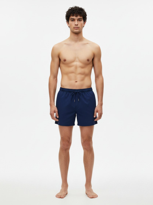 Model wearing CÔTE CHIC Monaco Blue swim shorts, front view